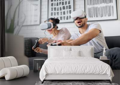 Virtual reality, gaming and metaverse with a couple playing video games in their home together for fun or enjoyment. VR, game and 3d ai with a man and woman gamer bonding in a house living room Wall mural