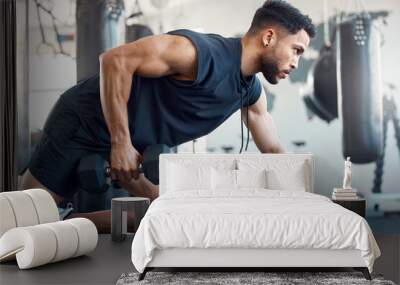 A bad day can be made better by going to the gym. Shot of a sporty young man exercising with a dumbbell in a gym. Wall mural