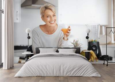 A healthy diet reflects on the outside. Shot of a woman holding a glass of juice in her kitchen. Wall mural