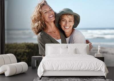 Best friends for life. Cropped shot of two attractive mature women hugging while standing on the beach. Wall mural