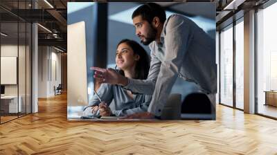 Business moves on when staff gets along. Shot of a young man helping his colleague in a call centre late at night. Wall mural