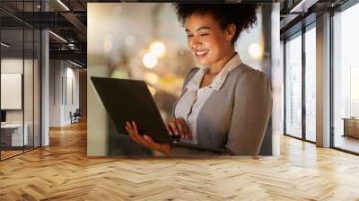 Business woman doing research on the internet with a laptop in a corporate modern office. Working lady browsing website or reading a finance blog on a computer. Happy female networking on technology. Wall mural