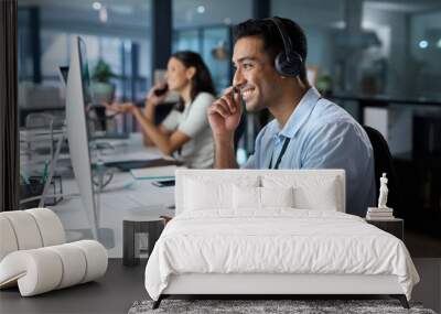 Dedicated service creates dedicated customers. Shot of a young man using a headset and computer in a modern office. Wall mural