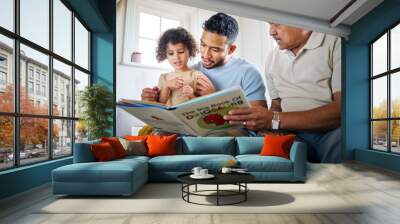 Family time comes in various forms. Shot of a little girl reading a book with her father and grandfather at home. Wall mural