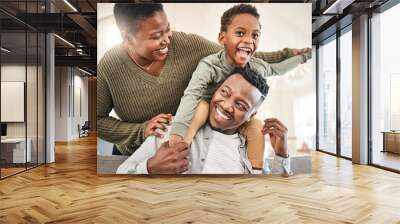 Family time is for laughter and fun. Shot of a happy young family playing together on the sofa at home. Wall mural