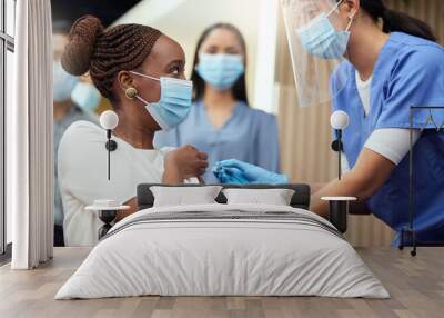 Getting her booster shot. Cropped shot of an attractive young businesswoman getting her covid vaccination from a female nurse in the office. Wall mural