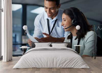 Great service makes a great impression. Shot of a young man and woman reading a document while working in a call centre. Wall mural