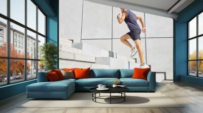 Head up and aim high. Low angle shot of a sporty young man running up a staircase while exercising outdoors. Wall mural