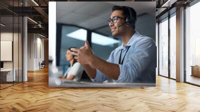 Let me make that a little easier for you. Shot of a young man using a headset and computer in a modern office. Wall mural