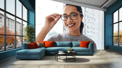 Loving the look of these. Shot of a young woman buying a new pair of glasses at an optometrist store. Wall mural