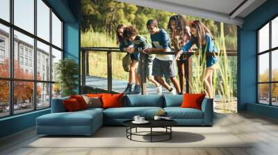 Nature is the new classroom. Shot of a group of teenagers standing on a bridge in nature at summer camp. Wall mural