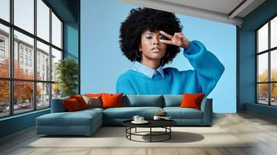 Portrait, young and black woman shows peace, sign and with blue studio background, afro and stylish look. Girl, happy lady and female with confident, relax and casual or funky outfit for fun day. Wall mural