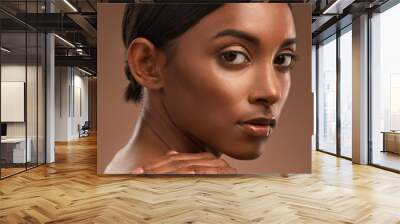 Standing on an overpass, in my miracle mile. Portrait of a beautiful young woman looking over her shoulder against a brown background. Wall mural