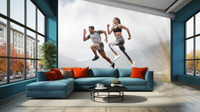 Started with a mile, now were at marathons. Shot of a sporty young man and woman running together outdoors. Wall mural