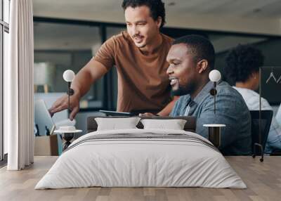 Teamwork makes everything easier. Shot of two young businessmen working together in an office. Wall mural