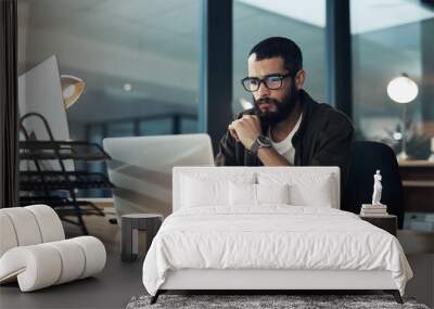 The more you focus the quicker youll find the solution. Shot of a young businessman using a laptop during a late night in a modern office. Wall mural