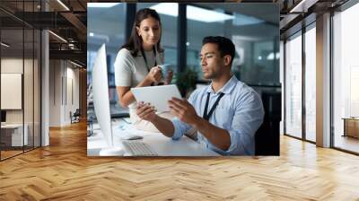 The team that does more, gets more. Shot of a young businessman and businesswoman using a digital tablet in a modern office. Wall mural