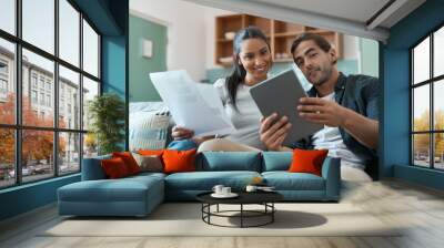 Working towards our future one step at a time. Shot of a young couple doing paperwork while using a digital tablet at home. Wall mural