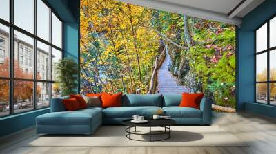 Fall foliage hills surround mossy cliffs with wood boardwalk hiking trail against rocks Wall mural