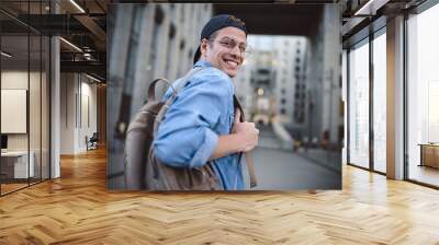 Cheerful young man with backpack enjoying walk the city Wall mural