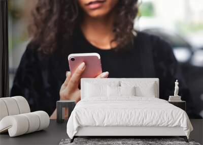 Closeup image of a beautiful mixed race woman holding, using and looking at smart phone with feeling happy. Wall mural