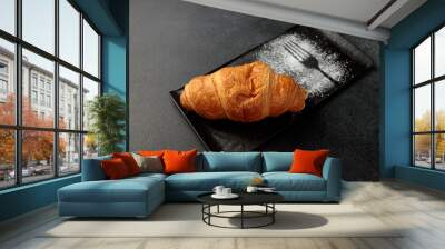 Crispy hot croissant on a black rectangular plate on a gray background Wall mural