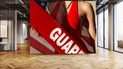 american woman lifeguard with rescue tube and whistle equipment against usa flag Wall mural