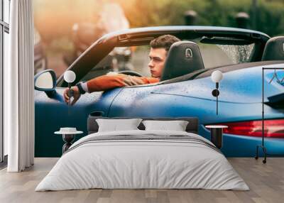 Succesful young adult handsome man drives luxury convirteble sport car at sunny day Wall mural