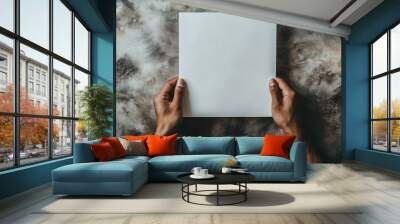 Two hands holding a blank white sheet of paper against table background Wall mural