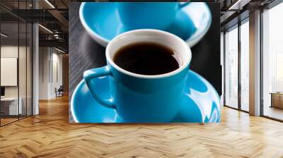 Vertical shot of two turquoise espresso cups on a black table Wall mural