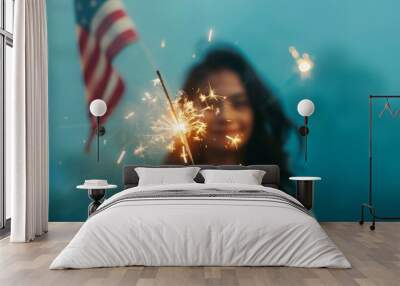 Close-up of a girl holding a sparkler and American flag with a pastel blue background and clear space for copy Wall mural