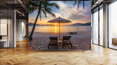 A beach scene with two lounge chairs and an umbrella. The sky is orange and the water is calm Wall mural