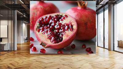 A close-up of a pomegranate sliced in half, revealing the bright red seeds inside.  Wall mural