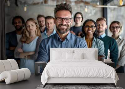 A group of people are smiling and posing for a photo. The man in the center is wearing glasses and has a big smile on his face. The group is diverse, with people of different ages and races Wall mural