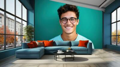 Portrait of happy young smiling man wearing glasses isolated on turquoise background. male student, professional employee or programmer Wall mural