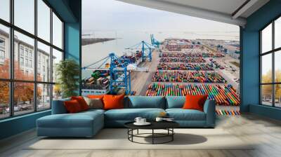 Container port with large ship being loaded and unloaded with gantry crane. International shipment and global freight transport and commerce. Aerial view of cargo harbor wharf. Wall mural