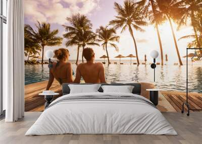 Couple enjoying beach vacation holidays at tropical resort with swimming pool and coconut palm trees near the coast with beautiful landscape at sunset, honeymoon destination Wall mural