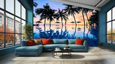 Summer beach holiday vacation destination, luxurious beachfront resort swimming pool with tropical landscape, quiet warm sunset, silhouette and reflection in water Wall mural