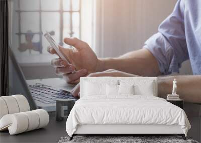 Young man working from home with laptop computer and smartphone Wall mural