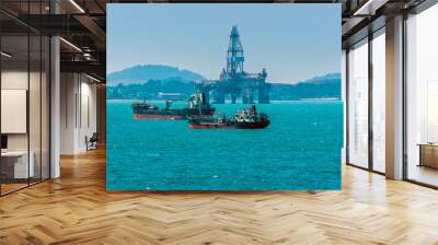 A group of small tankers moored close to a drilling rig in the Singapore Straits in Asia in summertime Wall mural