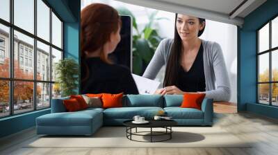 Tell me something about yourself thats not in your resume. Shot of two young professionals having a discussion at a desk. Wall mural