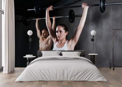 Training to become fighting fit. two people lifting barbells during a gym workout. Wall mural