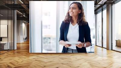 Working smarter is always worth it. Shot of a young businesswoman using a digital tablet in an office. Wall mural