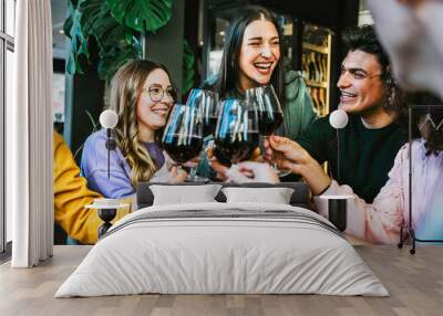 Group of  friends clinking and cheers  red wine glasses sitting at table bar restaurant-Young people having fun and toasting wine together enjoying happy hour at winery pub-Lifestyle concept  Wall mural