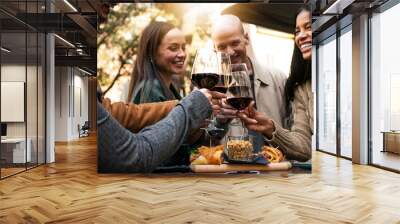 Young smiling friends toasting red wine at restaurant pub at happy hour with appetizers  - Happy people having fun together at winery bar and eating food  - Dinning life style concept. focus on glass  Wall mural