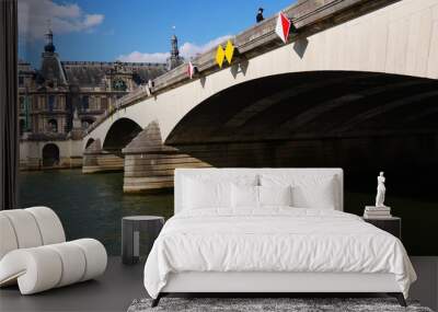 Gros plan d'un grand pont de pierre historique de Paris et de la Seine, sous un beau, jeu d'ombre et de lumière de soleil, fleuve vert, panneaux de signalisation de bateaux, direction, sous ciel bleu Wall mural