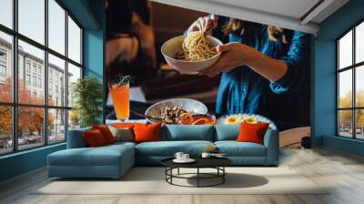 woman serving herself spaghetti noodles over table full of food Wall mural