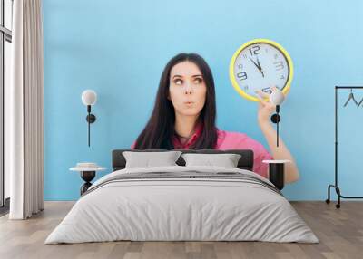 Cheerful Woman Holding a Clock on a Blue Background Wall mural