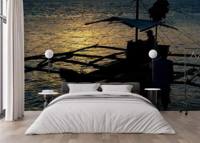 Silhouette of a fisherman on board a boat against the golden hour of sunset Wall mural