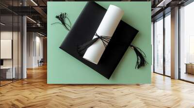 Top view of a black graduation cap and a rolled diploma with a red ribbon placed on a vibrant background. Promotion, poster Wall mural